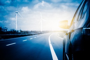 Wind turbines on landscape along empty road against sky.